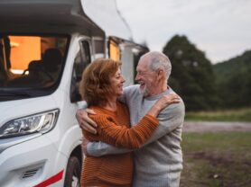 Senior,Couple,Standing,And,Hugging,Outdoors,At,Dusk,,Caravan,Holiday